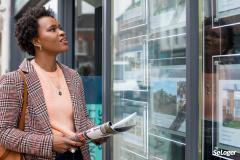 Une femme devant une agence immobilière