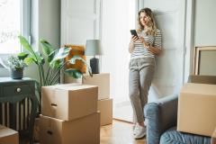 femme sur son téléphone dans un appartement entourée de cartons