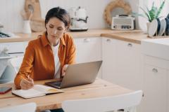 femme concentrée devant son ordinateur dans la cuisine