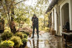 Un monsieur qui balaie sa terrasse sous la pluie