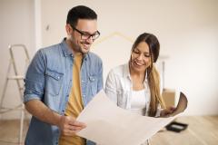 une femme et un homme regarde un document dans un appartement en chantier