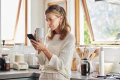 femme cinquante ans dans sa cuisine sur son téléphone