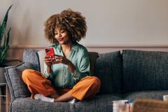 Femme sur son canapé jambes croisées en train de regarder son téléphone