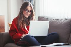 Jeune femme assise sur un canapé avec son ordinateur