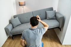 Un homme constatant que son logement est trop petit pour accueillir son canapé