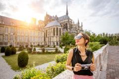 Une femme, un appareil photo à la main, devant la Cathédrale de Reims