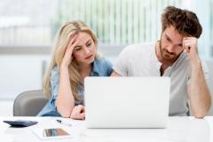 Un homme et une femme semblent dépités, assis côte à côte devant leur ordinateur