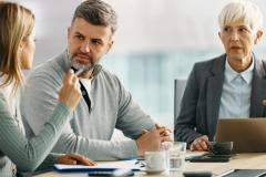 Un couple échange autour d'un bureau lors d'un rendez-vous avec sa banquière