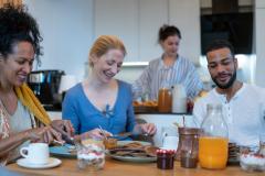 Quatre personnes prennent le petit-déjeuner ensemble autour d'une table à leur domicile