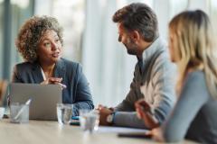 Un couple échange avec sa conseillère bancaire, assis à un bureau