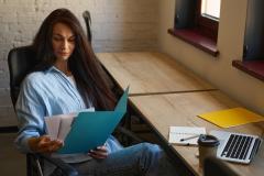 Une femme étudie avec attention un document papier qu'elle tient entre ses mains