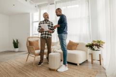 Deux hommes, debout dans un appartement, échangent au sujet d'un contrat