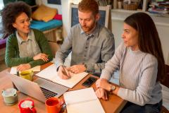 Trois personnes sont réunies autour d'une table de travail au domicile de l'une d'elles