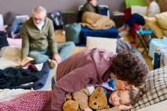 Un groupe de plusieurs personnes dorment sur des lits de fortune dans une seule et même pièce
