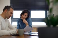 Un couple, assis autour d'une table, étudie avec attention un document au format papier