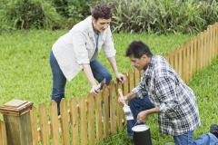 Un homme et une femme installent une petite clôture en bois commune en limite de leur terrain