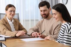 Un jeune couple signe les documents relatifs à l'achat de son nouveau logement chez le notaire