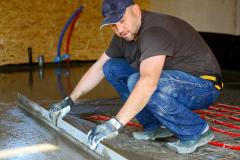 Un artisan procède à la pose d'un sol en béton en intérieur