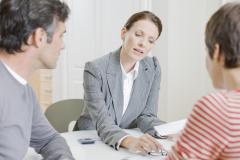 Une femme donne des explications à un couple de clients sur des documents au format papier
