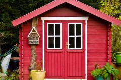 Petite maisonnette en bois rouge servant d'abri de jardin, en limite de propriété