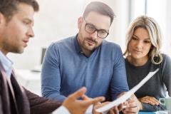 Un couple étudie des documents avec son banquier lors d'un rendez-vous