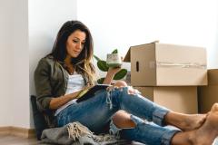 Femme répondant au quiz déménagement sur sa tablette au milieu de ses cartons