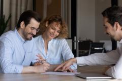 Un jeune couple signe des documents, guidé par son notaire