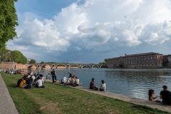 Des étudiants sont assis sur l'herbe sur les berges de la Garonne, à Toulouse, par une journée ensoleillée