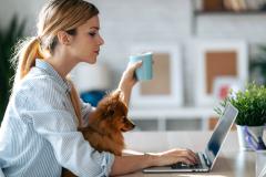 femme tient une tasse et recherche à faire un investissement immobilier devant son ordinateur