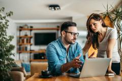 couple inquiet devant ordinateur se demande s'il doit faire remplacer son toit qui contient de l'amiante