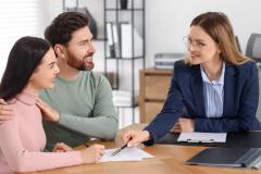 Un jeune couple consulte les documents remis par son notaire au cours d'un rendez-vous pour la signature d'un acte de vente