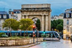 Passage du tram près de l’arche historique de Bordeaux au crépuscule