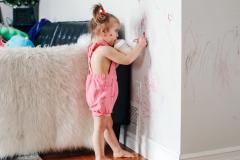 Une petite fille dessine avec un marqueur sur les murs blancs du salon