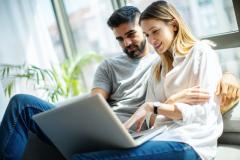 couple-regarde-son-ordinateur-adossé-à-la-baie-vitrée