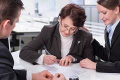Une femme âgée signe un document officiel chez le notaire