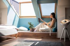 femme regarde son ordinateur portable installée sous son velux securisé