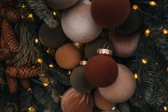 Boules de Noël allant du brun au safran accrochées sur un sapin