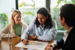 Un couple signe une offre d'achat sur les conseils d'un agent immobilier