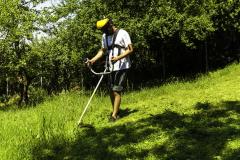 Un homme portant un équipement de protection assure le débroussaillement de son jardin