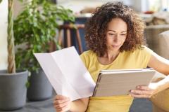 Une femme aux cheveux bouclés consulte ses comptes sur une tablette