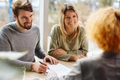 Un couple souriant valide les conditions d'un accord avec sa conseillère bancaire lors d'un rendez-vous