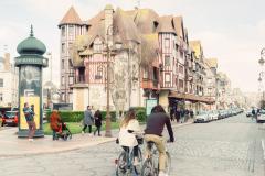 Un jeune couple arpente l'une des artères principales de Deauville à vélo