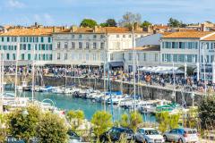 De nombreuses personnes se promènent sur les quais du port de plaisance de Saint-Martin-de-Ré, près de La Rochelle