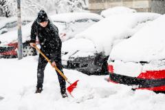 Un homme déneige le parking d'une copropriété à l'aide d'une pelle
