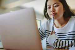 Une jeune femme d'origine asiatique fait des recherches sur son ordinateur