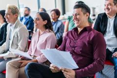 Un groupe de personnes assises côte à côte, tenant la convocation dans les mains, participe à une réunion de copropriété