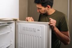 Un homme nettoie le joint de la porte de son congélateur avec une éponge