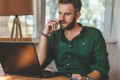 Un homme effectue des démarches administratives sur son pc portable, dans son salon