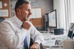 Un homme d'affaires étudie des documents sur son pc portable dans son bureau