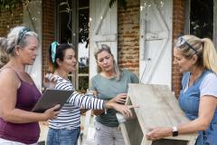 4 femmes échangent devant une maison en briques rouges au sujet des travaux en cours